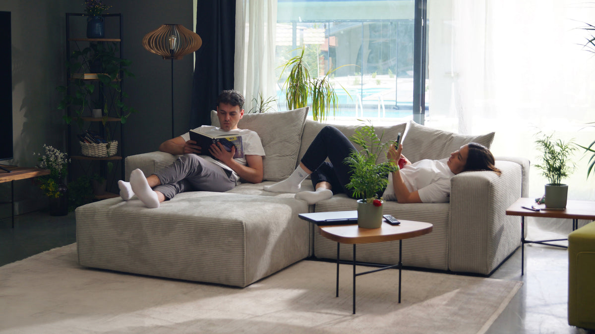 FEYDOM Bard L Sofa, auf dem zwei Personen am großen Fenster entspannen